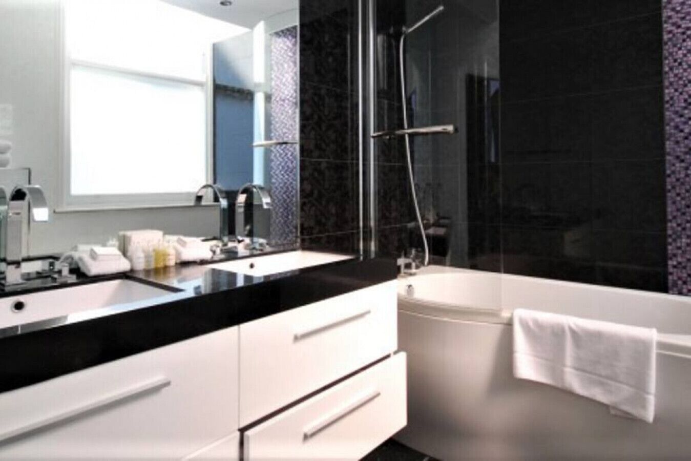A modern bathroom with a black countertop, white sink, and a glass-enclosed shower area.