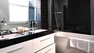 A modern bathroom with a black countertop, white sink, and a glass-enclosed shower area.