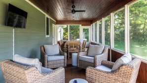 A covered porch with wicker furniture, a ceiling fan, and large windows offering a view of the outdoors. - New Pool, Hot Tub, Short Walk To Beach (Union Pier)