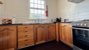 A kitchen with wooden cabinets, a stainless steel oven, a window, and a tiled backsplash.