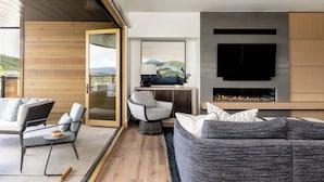 Una sala de estar moderna con chimenea, un televisor grande y vistas al exterior.