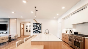 Una cocina moderna con una isla central, horno empotrado y una zona de comedor con una mesa larga y sillas.