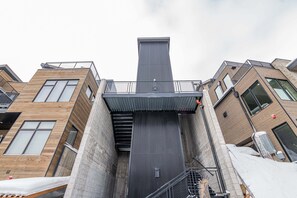 Un edificio a più piani con ascensore centrale, balconi e facciate in mattoni e legno.