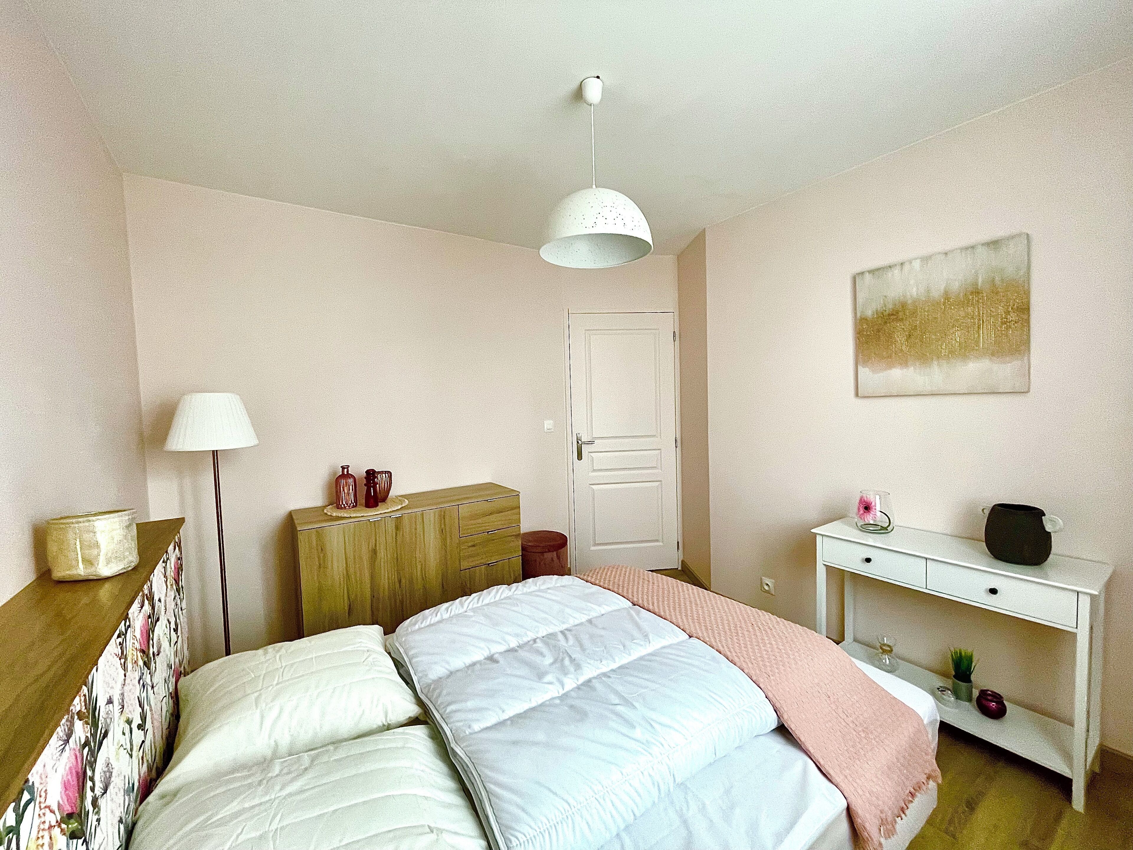 Un dormitorio con cama, cómoda, mesita de noche, lámpara y una puerta.