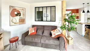 Een moderne woonkamer met een grijze bank, een klein rond tafeltje en een groot abstract schilderij.