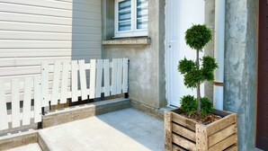 Een houten plantenbak met een kleine boom op een betonnen terras.