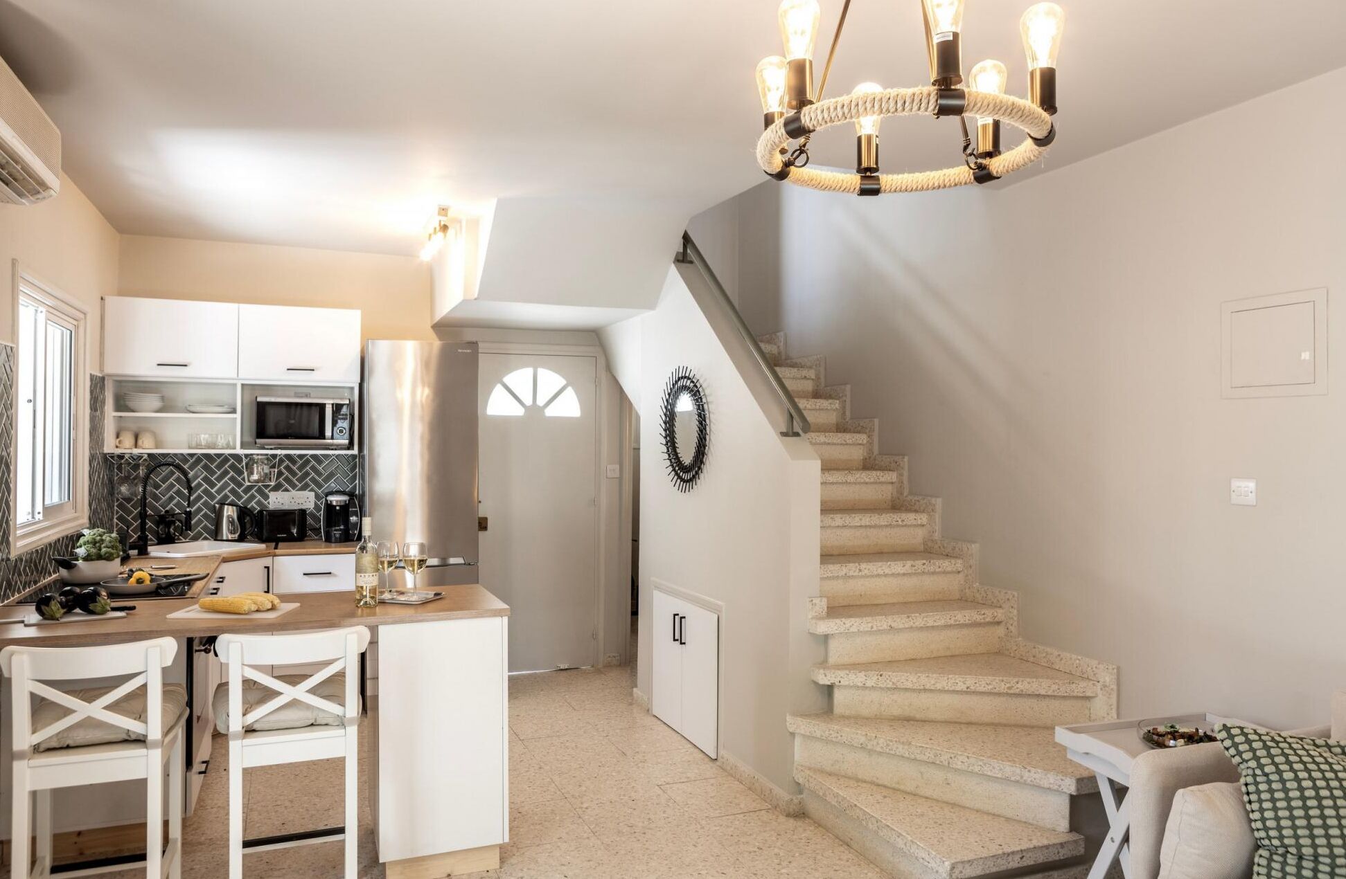 A modern kitchen with white cabinetry, a built-in microwave, and a dining area with white chairs.