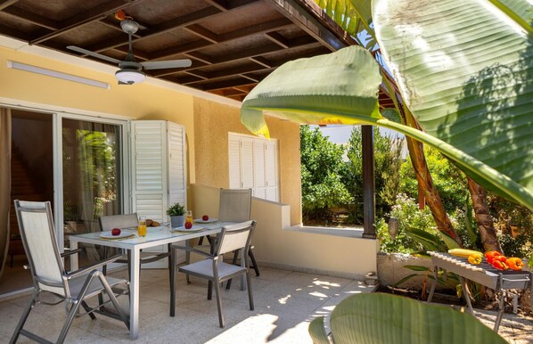 An outdoor patio with a table set for breakfast, including croissants and orange juice. - Anas Kiti Seaside Villa (Pervolia)