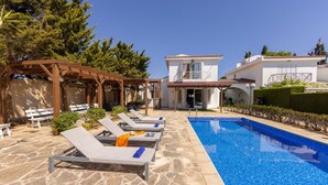 A pool area with lounge chairs, a pergola, and a clear blue pool. - Protaras Apollon Seaside Villa (Paralimni)
