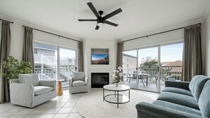 Ein geräumiges Wohnzimmer mit Kamin, Deckenventilator und großen Fenstern mit Blick auf die Stadt.