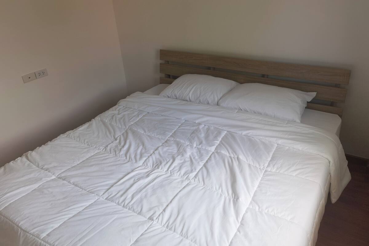 Un lit bien fait, avec une tête de lit en bois et une literie blanche.