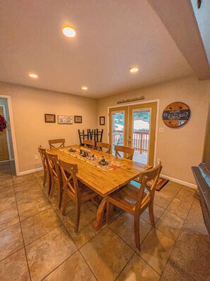 Un coin repas avec une table en bois, des chaises et une vue à travers une porte vitrée.