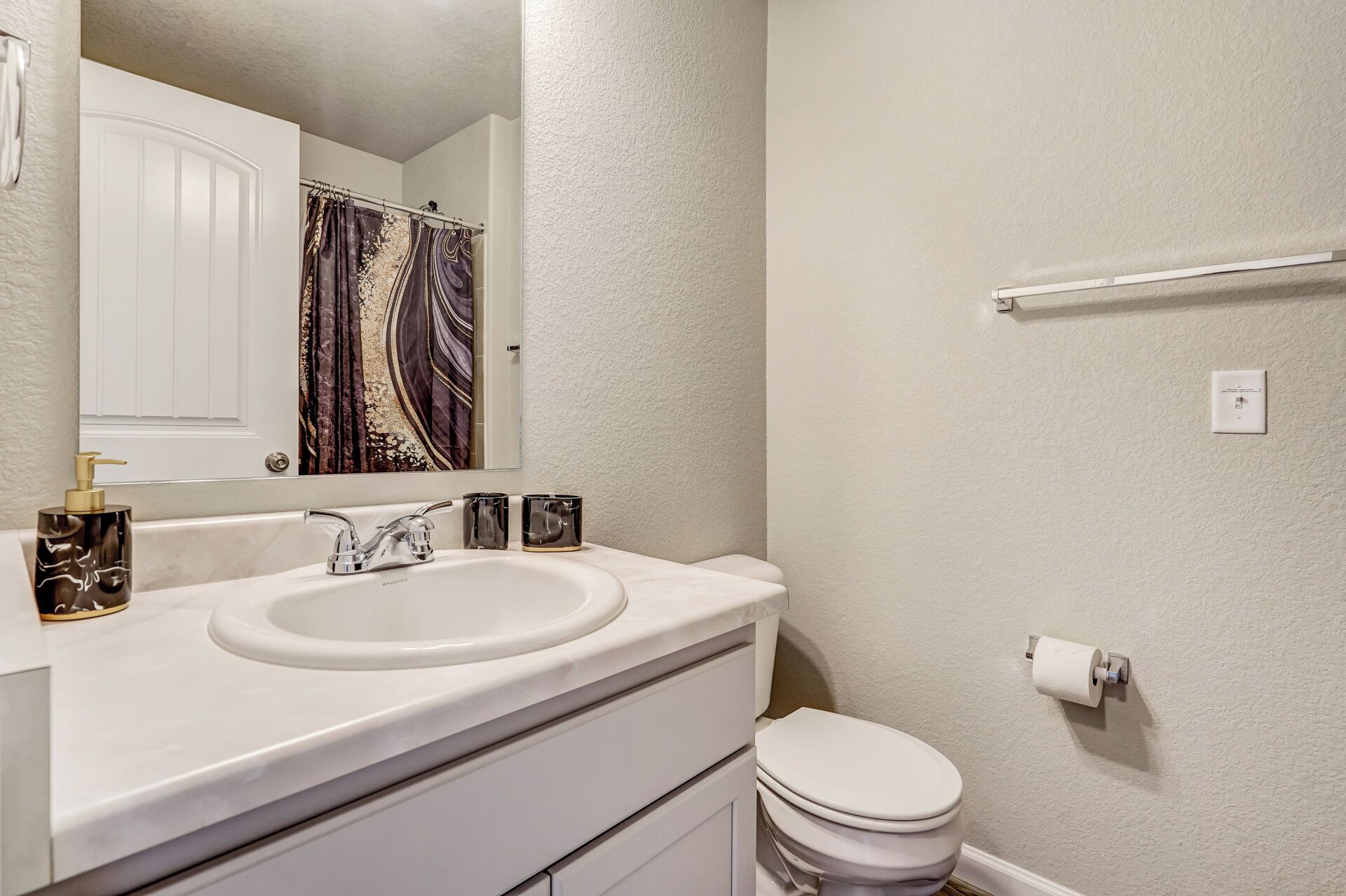 A bathroom with a white sink, a mirror, a toilet, and a towel rack.