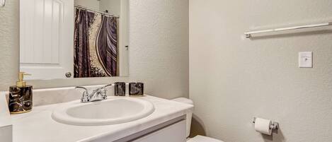 A bathroom with a white sink, a mirror, a toilet, and a towel rack.