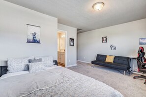 A bedroom with a bed, a black couch, and a gaming chair.