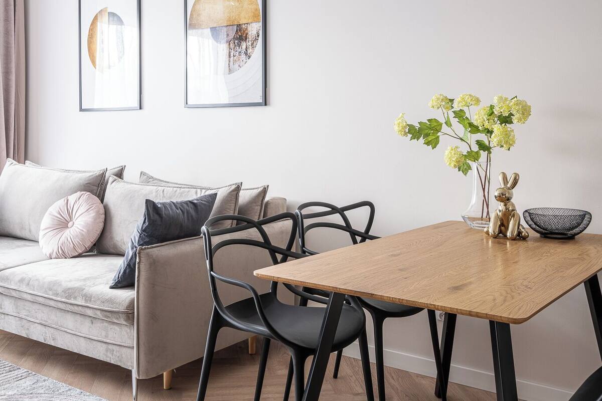 A modern dining area with a wooden table, black chairs, and a hanging light fixture.