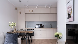 A modern kitchen with a dining area, featuring a herringbone wood floor, white cabinetry, and a pendant light fixture. - RentPlanet - Nowa Manufaktura (Wroclaw)