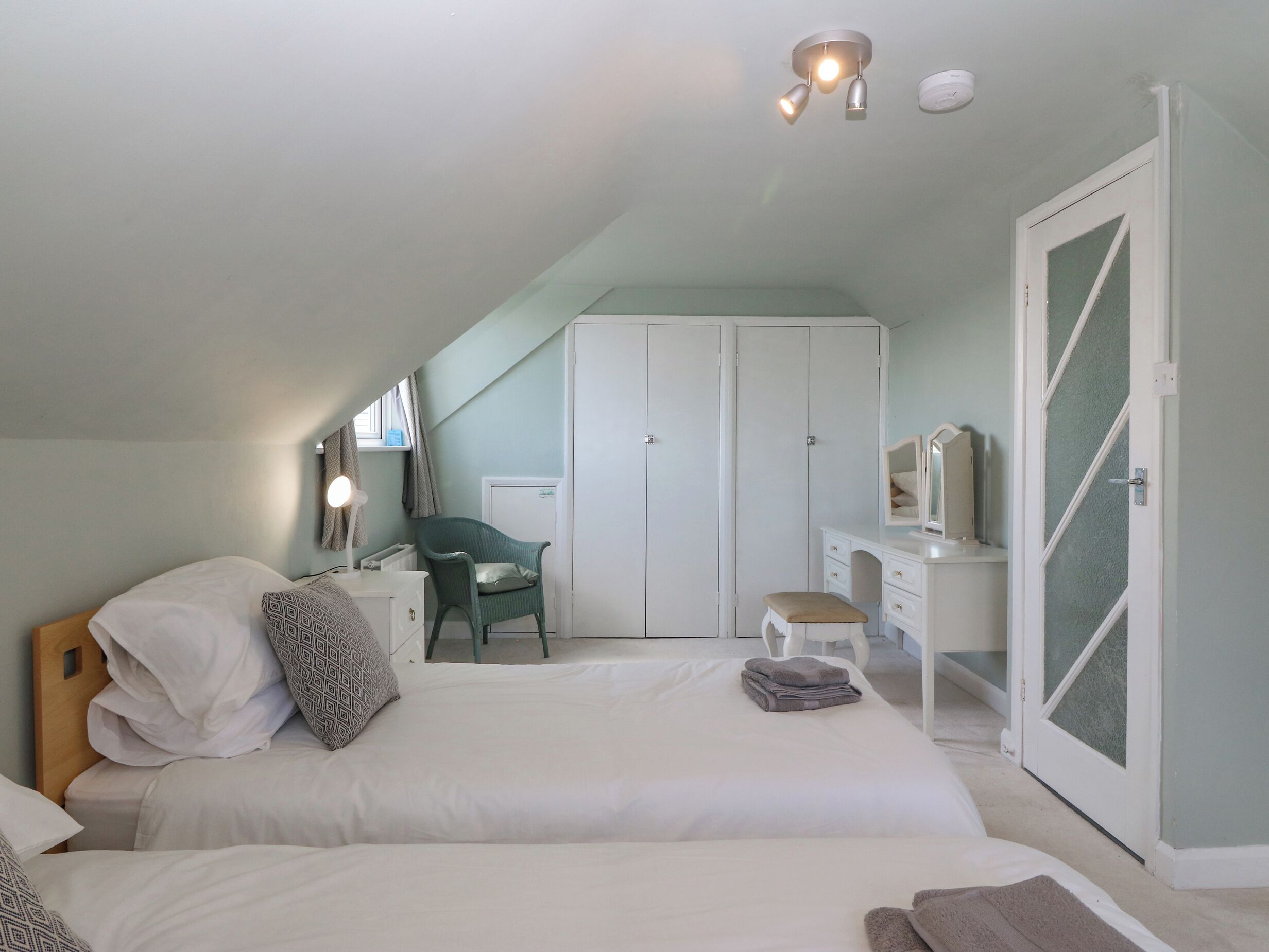 A bedroom with a bed, a desk, a chair, and a wardrobe.