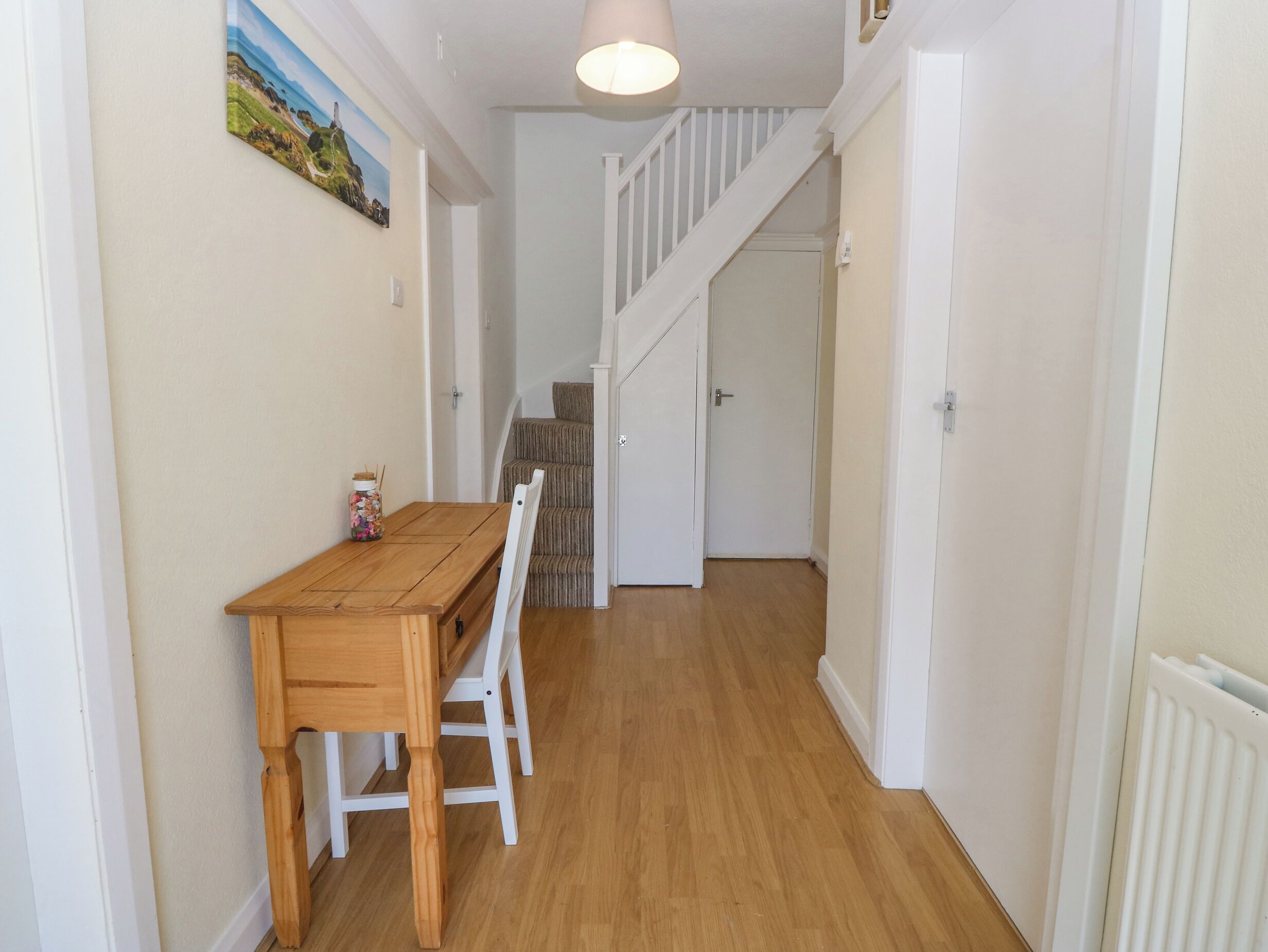 A hallway with a wooden table and chairs, a staircase, and a door leading to another room.