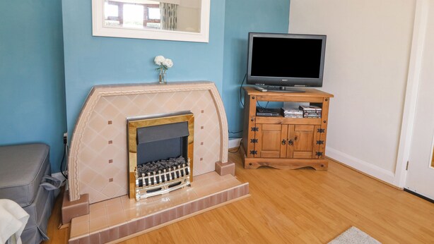 Ein Wohnzimmer mit Kamin, einem Fernseher auf einem Holzständer und einem Spiegel über dem Kamin.