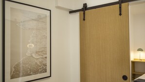 Et værelse med en skydedør, et billede i ramme på væggen og en lampe på et natbord.