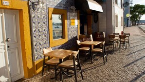 Un café con mesas al aire libre, una pared de azulejos y vistas al agua.