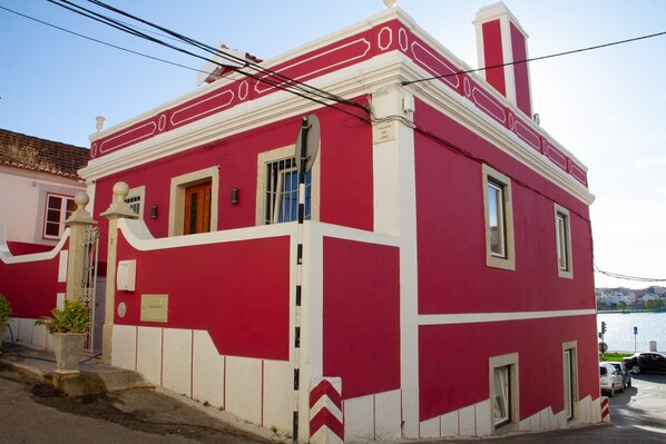 A red and white building with a traditional architectural style, featuring a prominent chimney, a door, and windows.