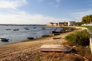 A beach with boats, a sandy shore, and buildings in the background.