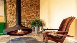 Un muro de piedra, una chimenea, una silla de madera y una planta en maceta.