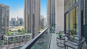 Un immeuble de grande hauteur doté d’un balcon aménagé avec du mobilier d’extérieur et offrant une vue sur le paysage urbain.