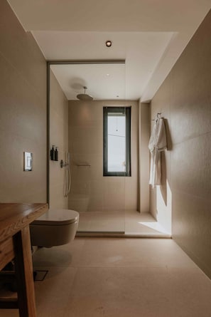 Un baño moderno con ducha, inodoro y un banco de madera.