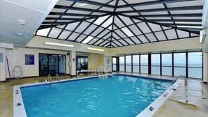 An indoor swimming pool with a high ceiling and large windows. - Direct Ocean Front Studio at the Golden Sands with Indoor Pool, Gym and Saunas (Ocean City)