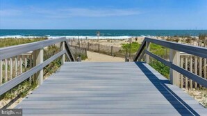 A wooden boardwalk leading to a beach with a fence on one side. - Direct Ocean Front Studio at the Golden Sands with Indoor Pool, Gym and Saunas (Ocean City)