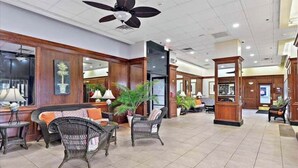 A lobby with wicker furniture, potted plants, and a reception desk. - Direct Ocean Front Studio at the Golden Sands with Indoor Pool, Gym and Saunas (Ocean City)
