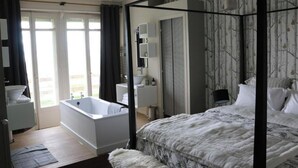 A bedroom with a four-poster bed, a large window, and a bathroom with a bathtub. - Maison Valmer - L'armateur, Élégant Penthouse Classé 4 Étoiles (Le Havre)