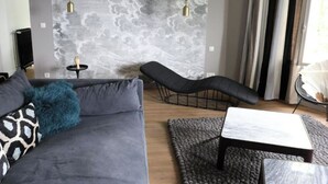 A modern living room with a grey sofa, a black lounge chair, and a small table. - Maison Valmer - L'armateur, Élégant Penthouse Classé 4 Étoiles (Le Havre)
