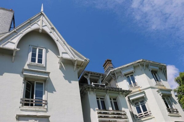 A building with a steeply pitched roof, multiple windows, and a visible chimney.