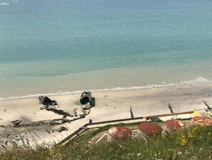 A beach with a large shipwreck and a fence.