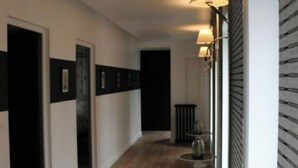 A hallway with wooden flooring, black and white walls, and wall-mounted lamps. - Maison Valmer - L'armateur, Élégant Penthouse Classé 4 Étoiles (Le Havre)
