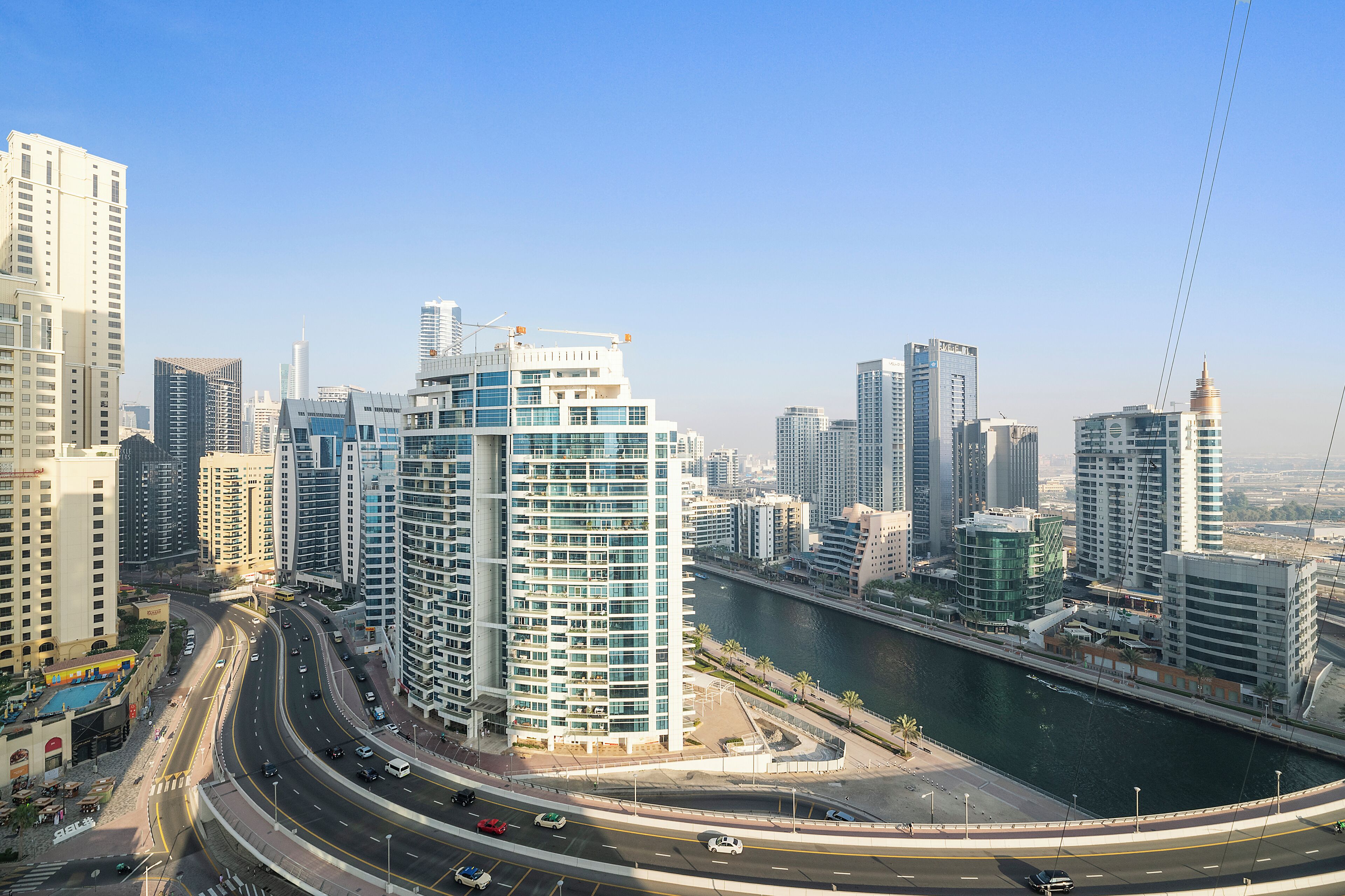 A cityscape with modern high-rise buildings, a river, and a multi-level highway.