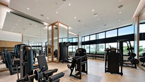 Uma academia moderna com diversos equipamentos de ginástica, amplas janelas e um layout espaçoso e limpo.