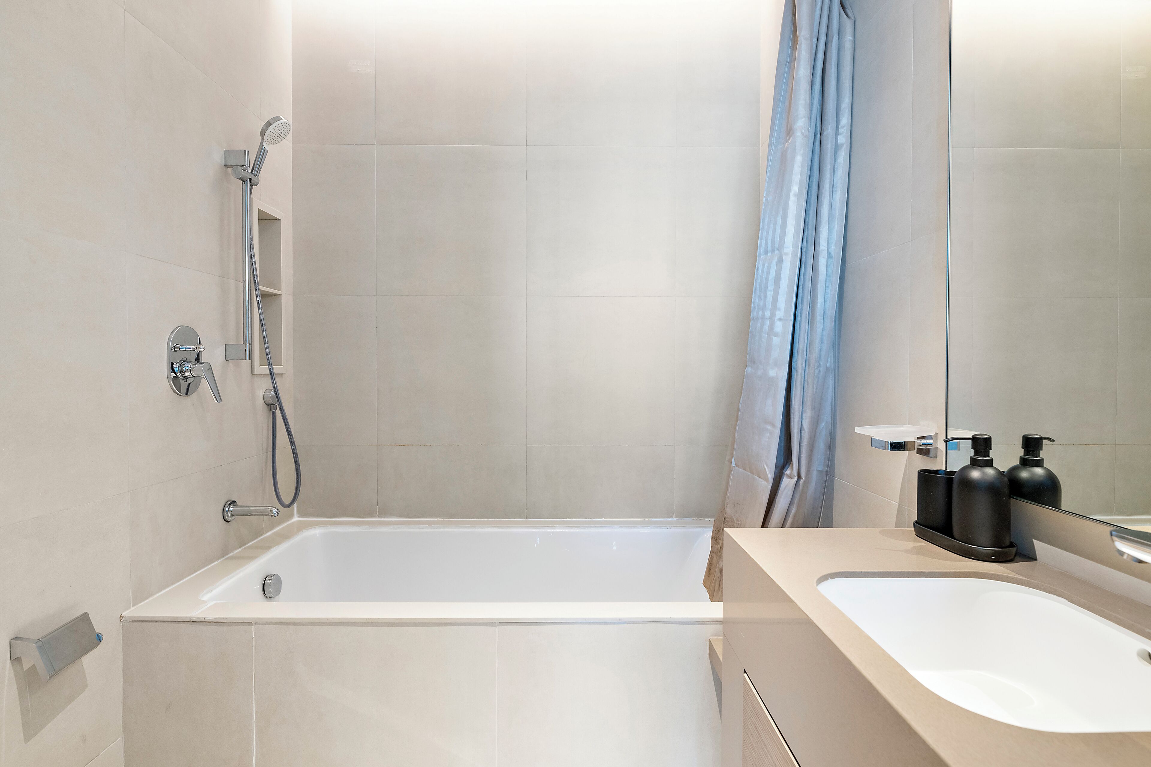 A modern bathroom with a bathtub, shower, and sink.