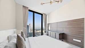 Quarto de hotel moderno com uma cama grande, vista da cidade e uma mesa embutida.