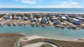 Vista aérea de una zona residencial costera con casas, muelles y una playa.