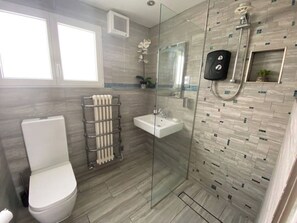 Une salle de bain moderne avec une douche à parois de verre, un lavabo blanc et des toilettes.