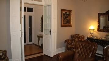 Una habitación con un sillón de cuero marrón, una puerta de madera, una mesita y una lámpara.