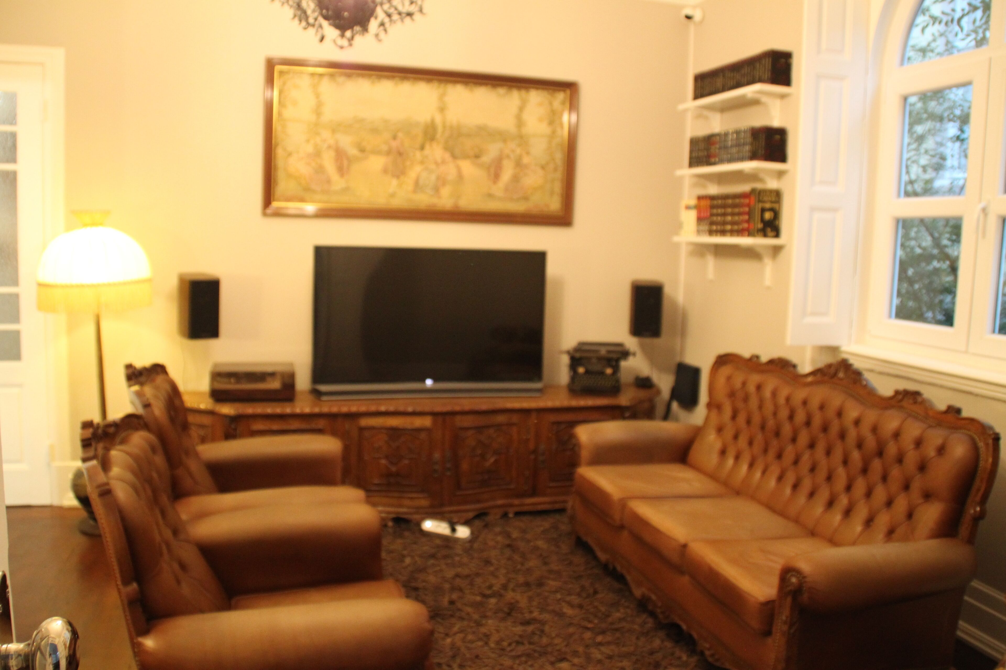 Ein Wohnzimmer mit einem großen Flachbildfernseher, Ledersofas, einer Holz-Unterhaltungseinrichtung und Bücherregalen.