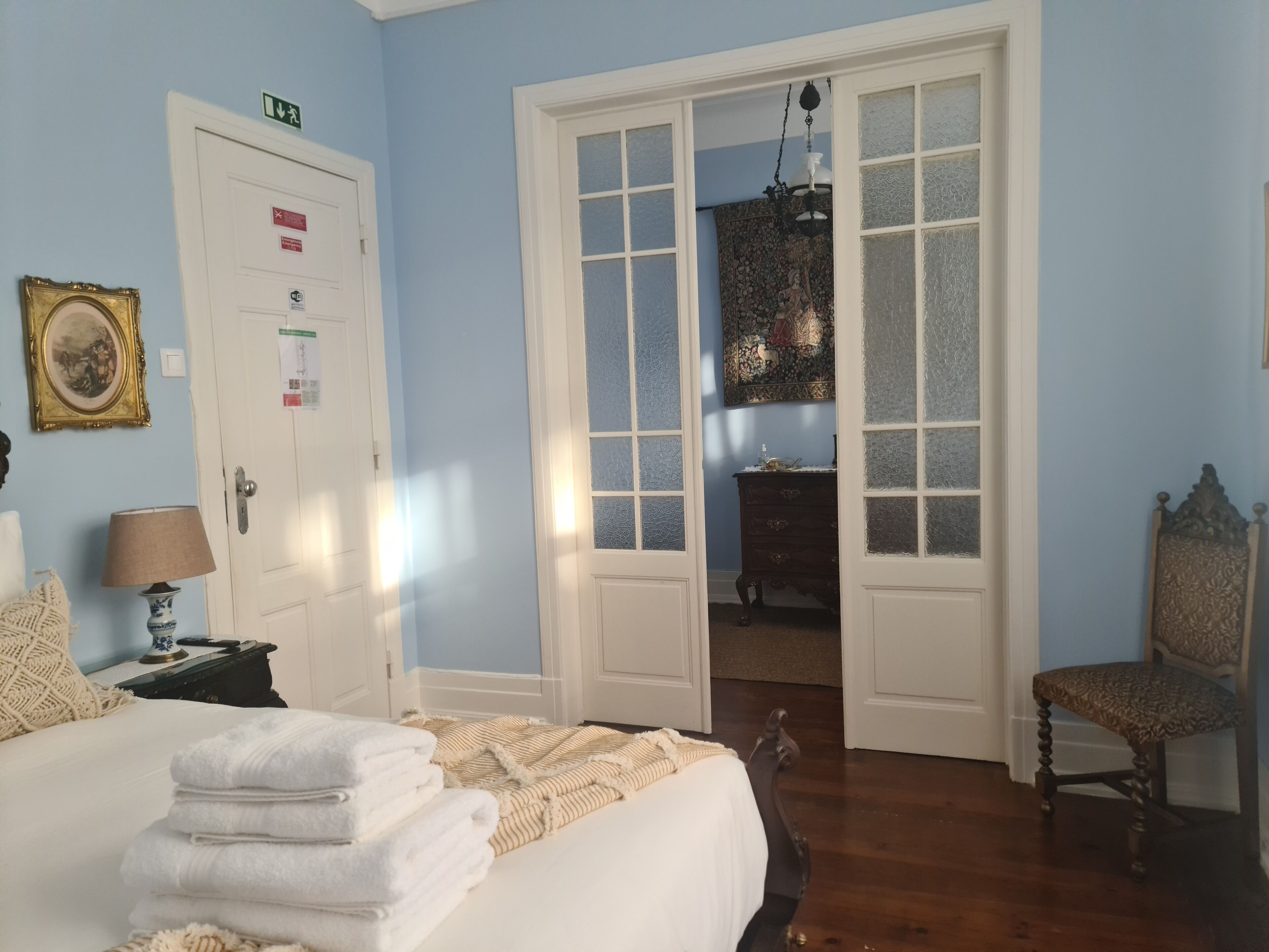 A bedroom with a bed, a dresser, a chair, and a door leading to another room.