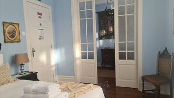 A bedroom with a bed, a dresser, a chair, and a door leading to another room.