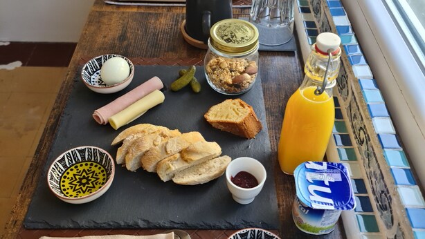 A breakfast table with various food items, a bottle of orange juice, and a window view.